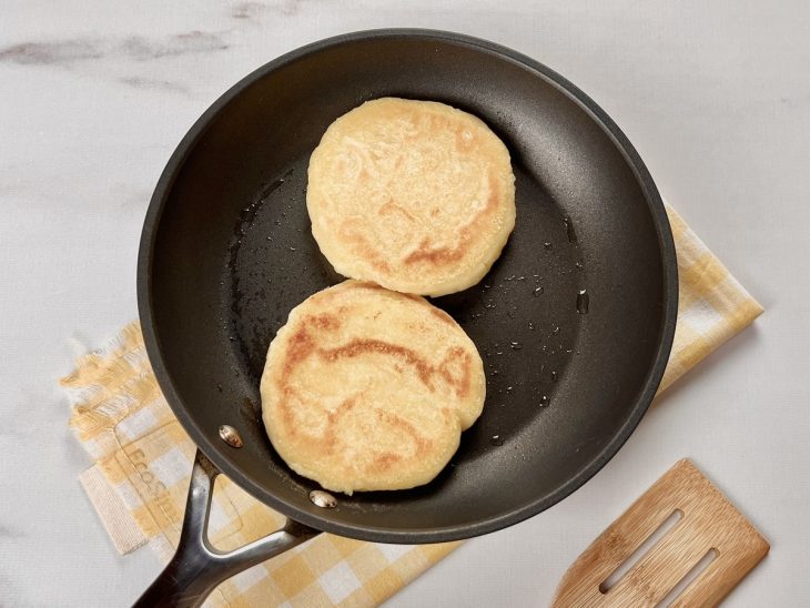 Uma frigideira com as arepas fritas.