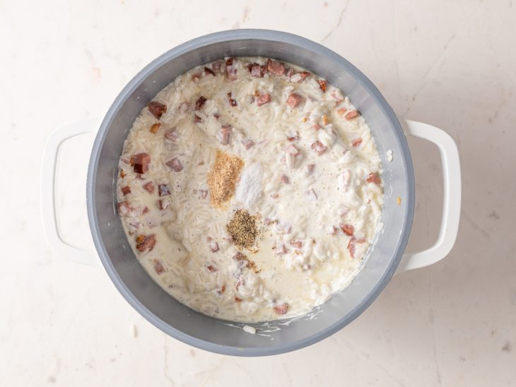 panela com arroz cozido, cubinhos de calabresa, creme de leite e temperos