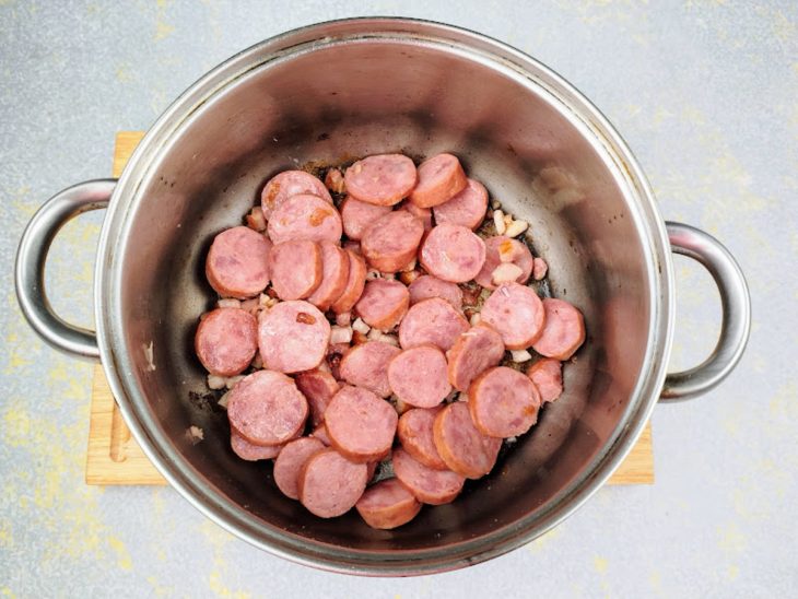 Panela grande com bacon e calabresa fritando no azeite.