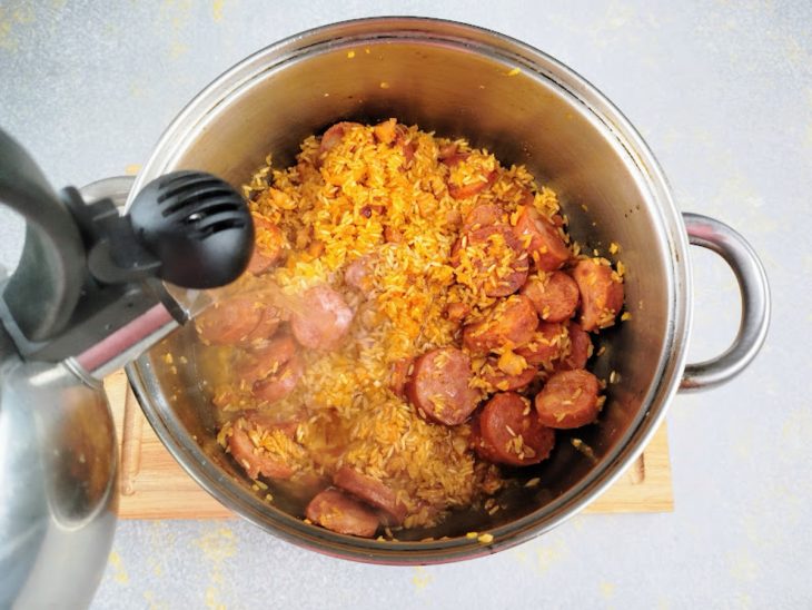 Água sendo adicionada na panela com a mistura de ingredientes.