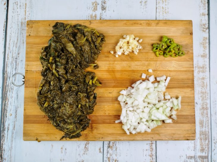 tábua com folhas de vinagreira, alho, cebola e pimenta-de-cheiro cortadas