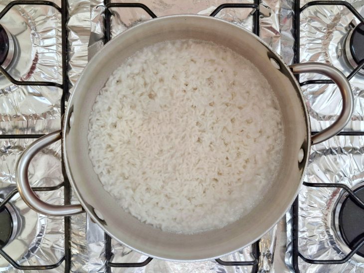 Arroz cozinhando na água em uma panela.