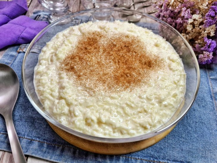 Arroz-doce cremoso com coco finalizado com canela e pronto para servir.