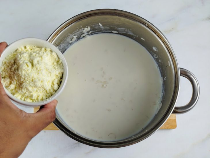 Leite integral, leite condensado, leite em pó e canela em pau adicionados a panela com arroz.