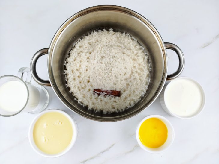 Arroz cozinhando em uma panela com água, canela em pau e sal.