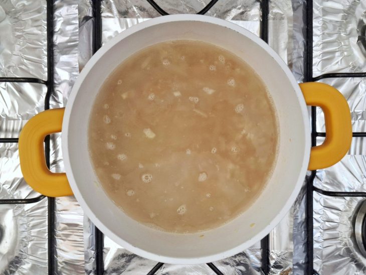 Arroz, água e sal adicionados na panela com cebola e alho refogados no azeite.