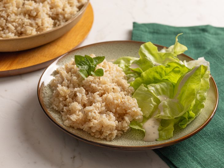 Arroz integral simples pronto para consumo e servido com salada de folhas.