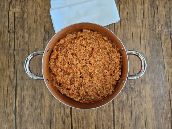 Uma panela contendo arroz cozido com o molho e temperos.