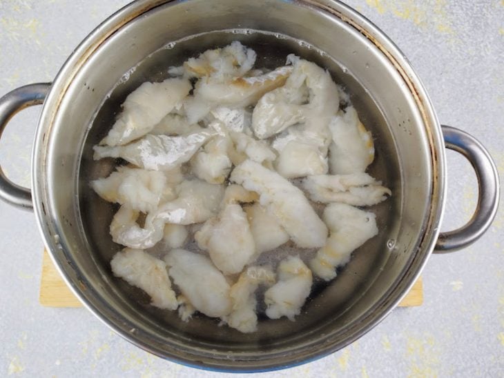 Postas de bacalhau em uma panela com água.