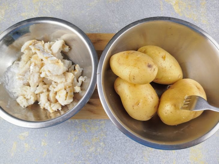 Bacalhau cozido e batatas cozidas em recipientes separados.