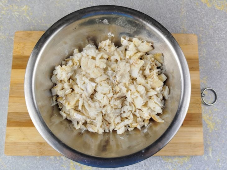 Bacalhau desfiado em um recipiente de alumínio.