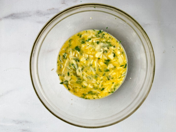 tigela com ovo batido, queijo ralado e salsinha