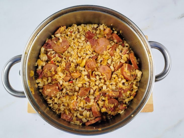 Arroz, temperos e feijão com caldo adicionados na panela.