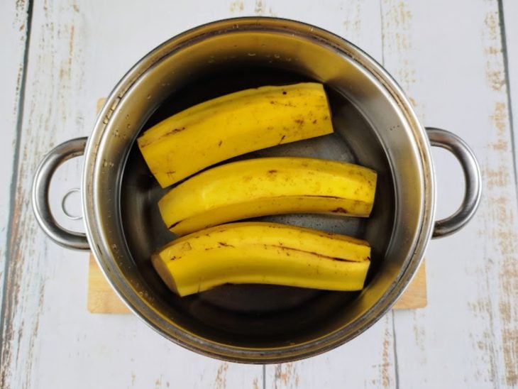 Uma panela com água e bananas aberta.