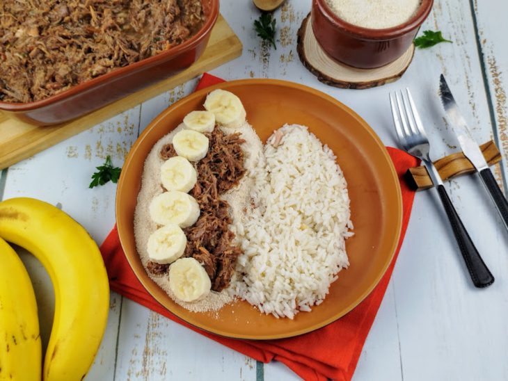 Barreado servido com farofa, arroz e banana