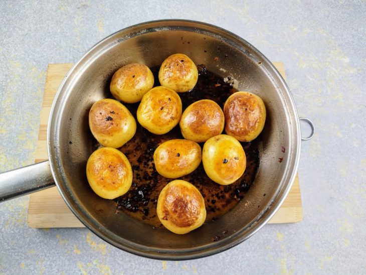 Batatas douradas em uma frigideira com azeite, manteiga, sal e pimenta calabresa