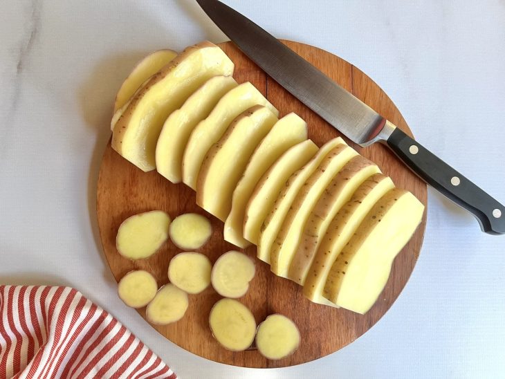 Uma tábua com as batatas fatiadas.