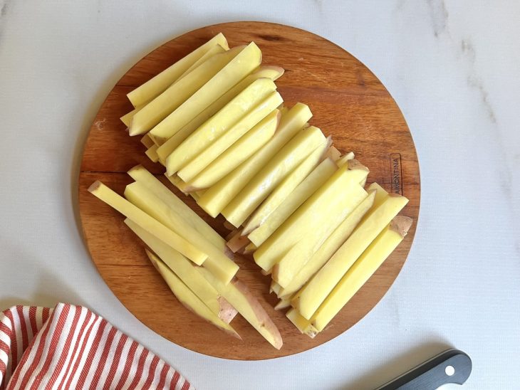 Uma tábua com as batatas cortadas em palitos.