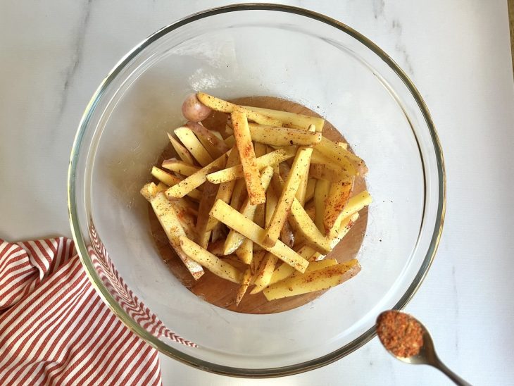 Uma tigela com as batatas cruas e temperadas.