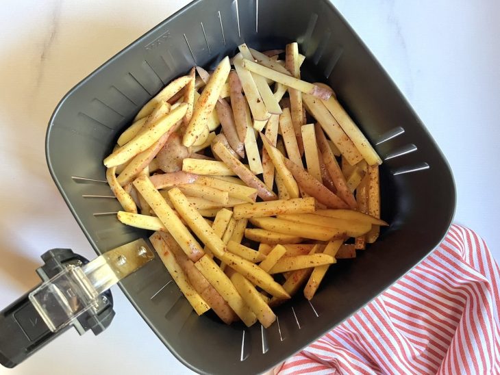 Uma cesta de airfryer com as batatas fritando.