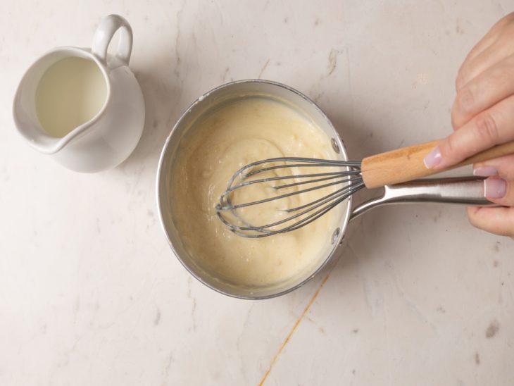 Leite sendo adicionado à panela para formar o molho branco.