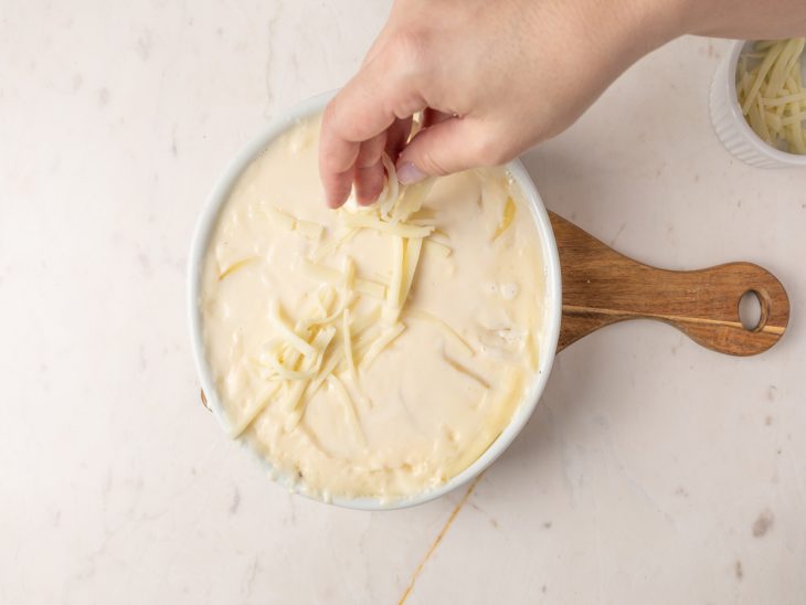 Queijo sendo salpicado sobre o refratário.