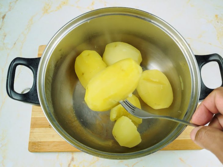 Batatas cozidas descascadas em uma panela.