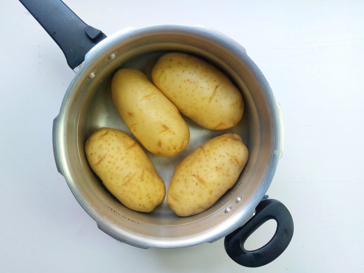 Uma panela com batatas cozidas na água.