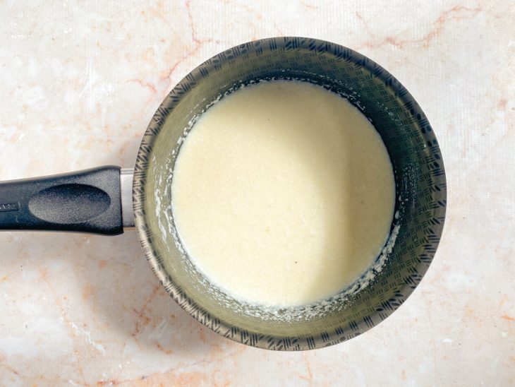 Leite condensado, coco ralado e margarina misturados em uma panela.