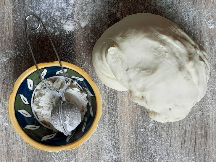 Massa em uma bancada e tigela com farinha de trigo