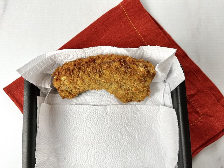 Um bife empanado e frito em um recipiente com papel toalha.