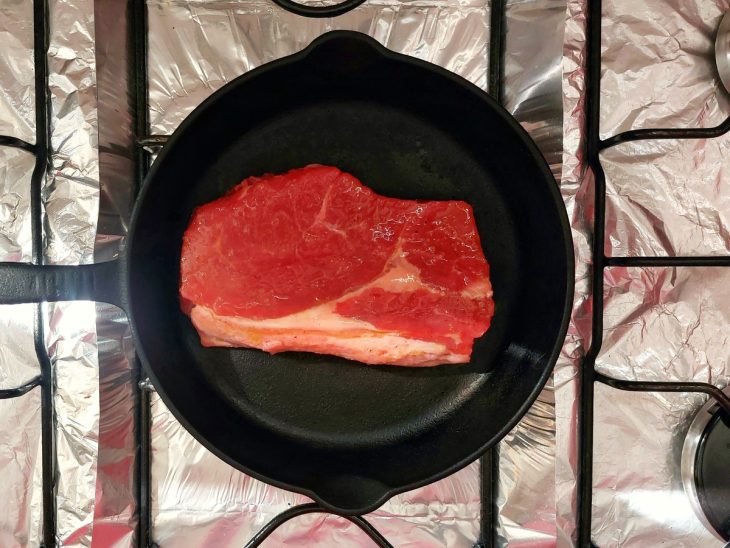 Uma frigideira selando um bife ancho.