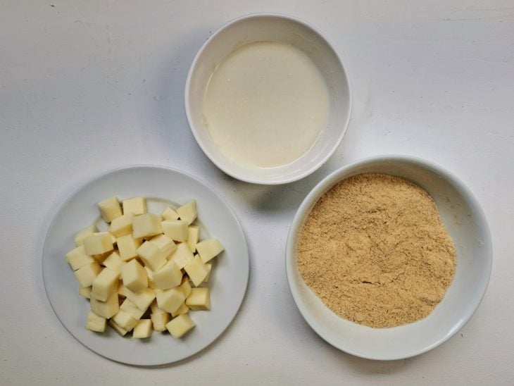 Recipientes com farinha de trigo, farinha de rosca e cubos de queijo.