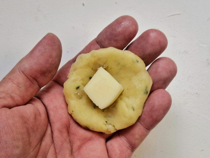 Bolinho de aipim sendo recheado.