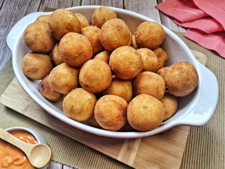 Um recipiente com bolinhos de aipim com queijo.