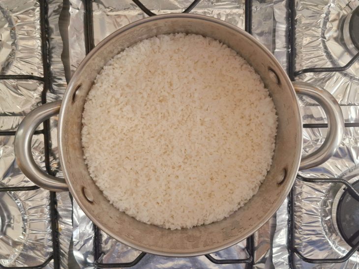 Panela ao fogo com água e arroz cozinhando.