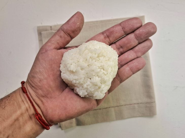 Bolinho de arroz sendo fechado e moldado.