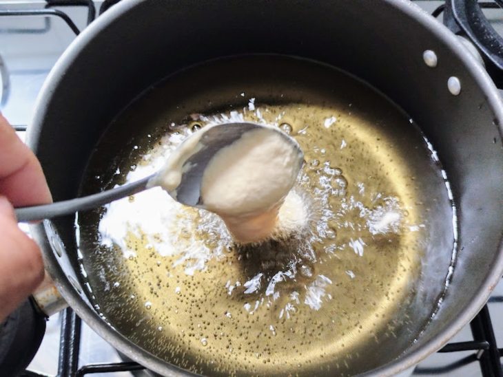 Porções de bolinho em óleo para fritar.