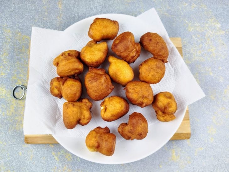 Bolinhos de chuva salgado fritos em um prato forrado com papel-toalha.