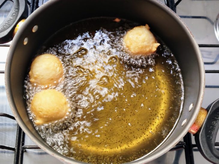 Bolinhos de chuva fritando em panela com óleo.