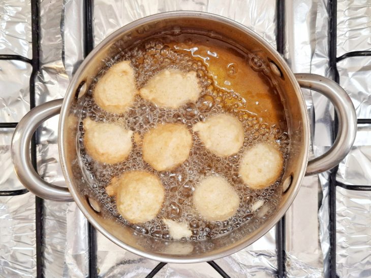 Bolinhos de chuva fritando na panela com óleo.