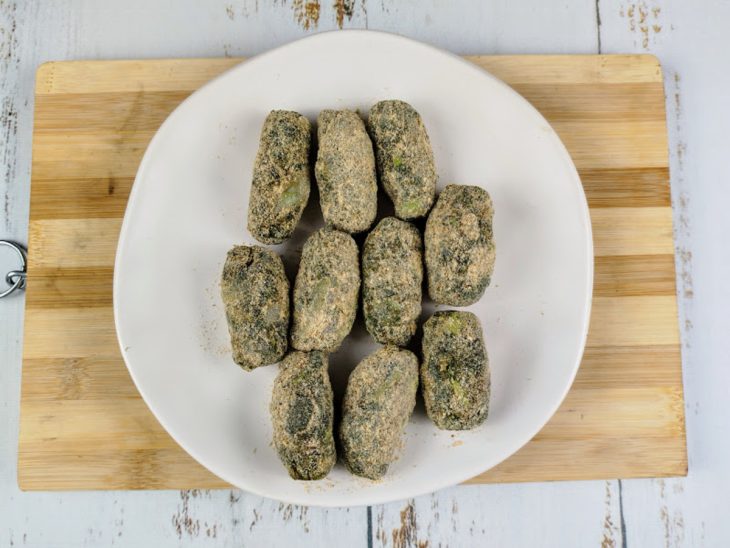 Bolinhos de taioba em formato de croquete em um prato sobre uma tábua