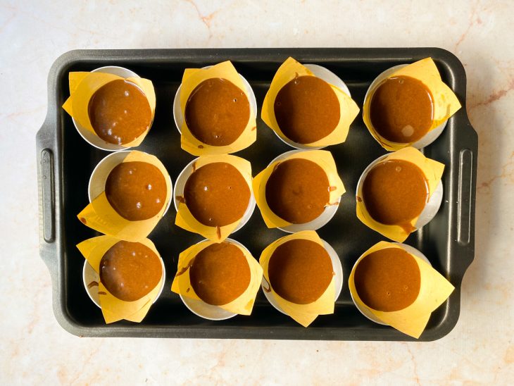 Forminhas preenchidas pela metade com massa de chocolate.