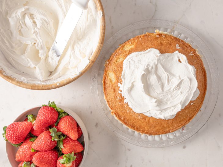 Bolo sendo coberto com a cobertura de chantilly.