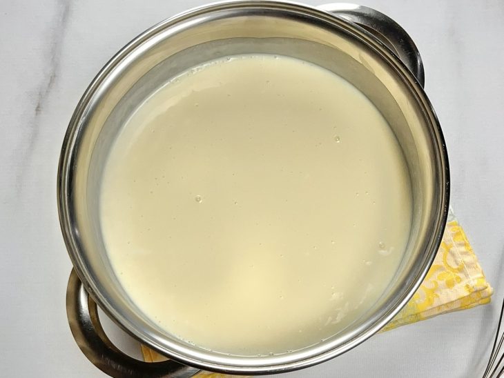 Uma panela contendo a mistura de leite condensado, leite em pó, creme de leite e leite de coco.