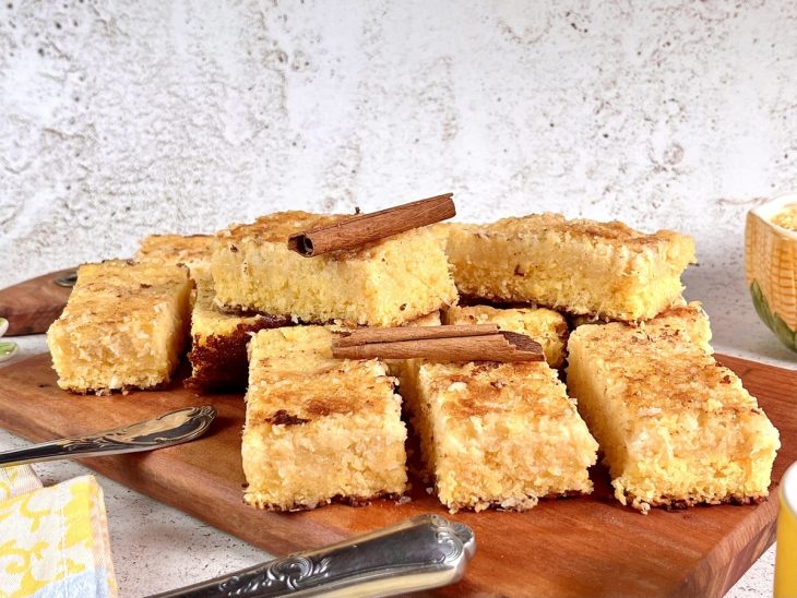 Uma tábua contendo bolo cremoso de flocão e coco.