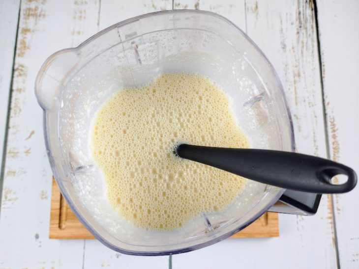 Um liquidificador com a mistura da massa e uma colher para incorporar os ingredientes.