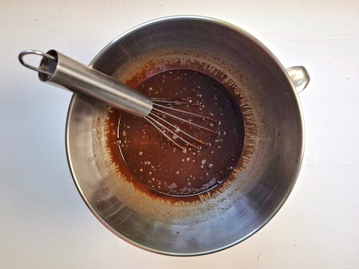 Chocolate em pedaços e café dissolvido incorporados em uma tigela.