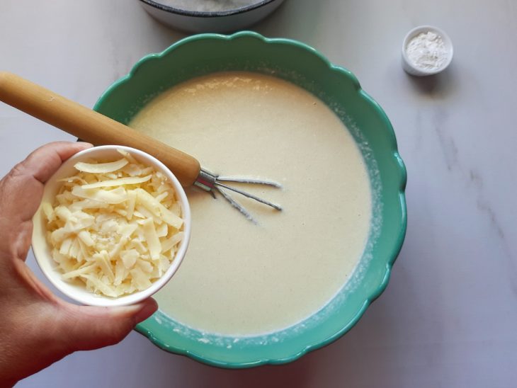 Um liquidificador contendo a mistura de ovos, óleo, leite, açúcar, leite de coco, arroz cozido, coco e queijo ralado.