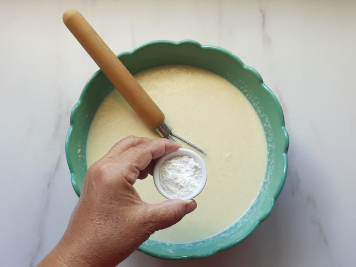 Um liquidificador contendo a mistura de ovos, óleo, leite, açúcar, leite de coco, arroz cozido, coco ralado, queijo ralado e fermento.